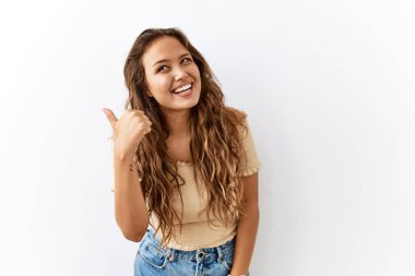 Güzel İspanyol kadın tek başına ayakta dikilirken mutlu yüzüyle gülümseyen ve başparmağıyla yan tarafı gösteren.. 