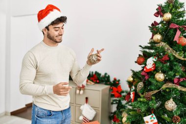 Genç İspanyol adam gülümsüyor mutlu noel ağacı süslüyor evde.