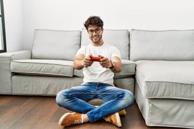 Evde video oyunu oynayarak kendine güvenen İspanyol genç adam.