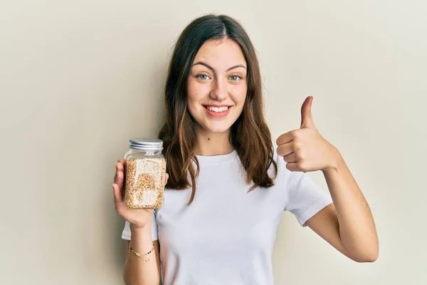 Young Brunette Woman Holding Jar Rice Smiling Happy Positive Thumb — стоковое фото