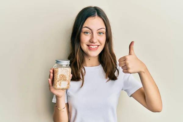 Young Brunette Woman Holding Jar Rice Smiling Happy Positive Thumb — Stockfoto