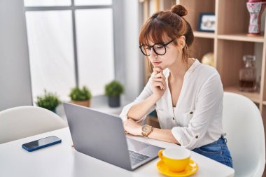 Young woman using laptop sitting on table at home
