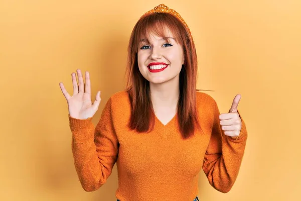 Rødhåret Ung Kvinde Iført Afslappet Orange Sweater Viser Peger Med - Stock-foto