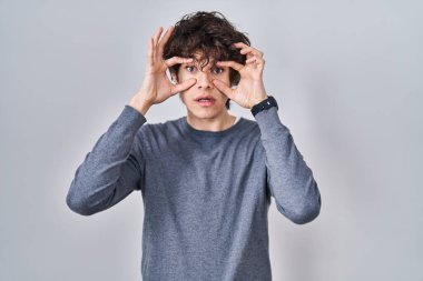 İzole edilmiş arka planda duran genç adam parmaklarıyla gözlerini açmaya çalışıyor, uykulu ve yorgun bir şekilde sabah yorgunluğu çekiyor. 