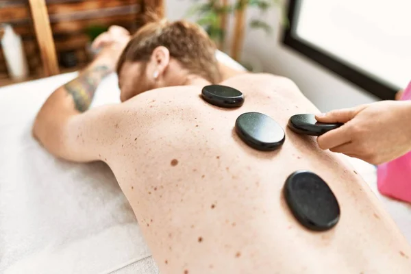 Ung Rödhårig Man Med Ryggmassage Med Svarta Stenar Skönhetscentret — Stockfoto