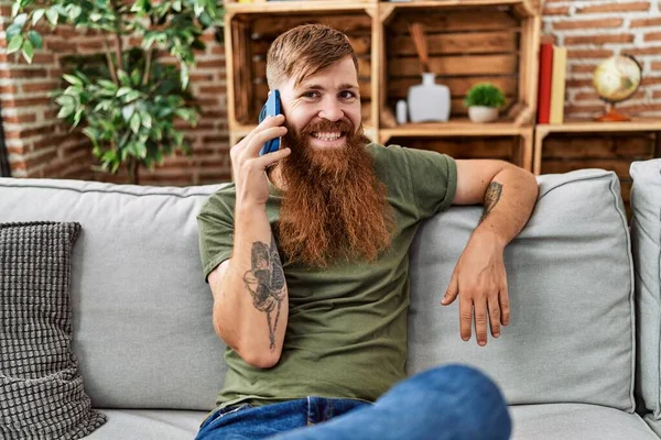 Ung Rödhårig Man Ler Tryggt Talar Smartphone Hemma — Stockfoto