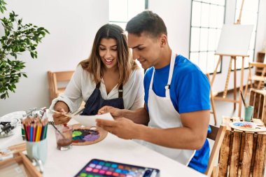 Sanat okulundaki masada oturmuş mutlu bir resim çizen iki öğrenci..