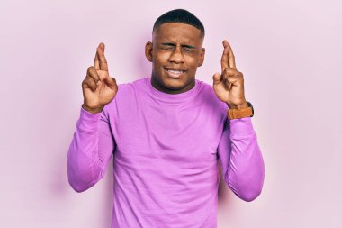 Sıradan pembe süveter giyen genç siyahi adam umut ve gözlerin kapalı gülümseyerek el sallıyor. Şans ve batıl inançlar. 