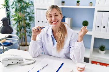 Güzel dişçi kadın diş fırçasıyla dişlerini nasıl fırçalayacağını anlatıyor gururla bağırıyor, zaferi kutluyor ve kollarını kaldırdığında çok heyecanlanıyor. 