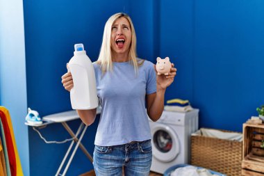 Çamaşır deterjanı şişesi ve domuz kumbarası tutan güzel bir kadın sinirli ve öfkeli çığlıklar atıyor. Öfkeyle bağırıyor.. 