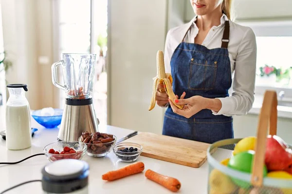 Joven Mujer Rubia Sonriendo Seguro Pelando Plátano Cocina —  Fotos de Stock