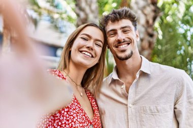 Genç İspanyol çift gülümseyerek şehirde fotoğraf çekerken mutlu oluyor..