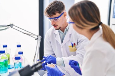 Genç adam ve kadın bilim adamları laboratuarda çalışıyorlar.