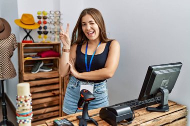 Genç esmer kadın perakende dükkanında açık mesajla pankart tutuyor. Gülümsüyor, kameraya göz kırpıyor ve parmaklarıyla zafer işareti yapıyor. İki numara.. 