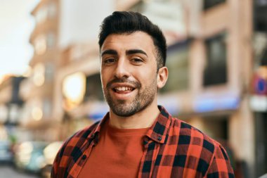 Genç İspanyol adam gülümseyerek şehirde mutlu mesut dikiliyor..