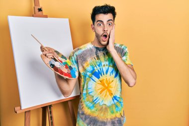 Genç, İspanyol asıllı bir adam palet üstüne palet çizerek ayakta duruyor. Korkuyor ve şoka uğruyor. Şaşırıyor ve şaşırıyor. 