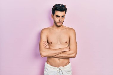 Mayo giyen genç, İspanyol bir adam. Tişörtsüz, şüpheci ve gergin. Yüzünde çapraz kollu tasvip etmeyen bir ifade var. negatif kişi. 