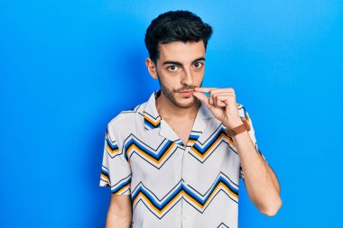 Gündelik kıyafetler giyen genç İspanyol adam ağzı ve dudakları parmaklarıyla kapanan fermuar gibi kapalı. gizli ve sessiz, tabu konuşması 