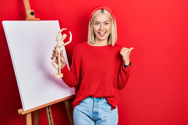 Beautiful Blonde Woman Holding Small Wooden Manikin Pointing Thumb Side — ストック写真