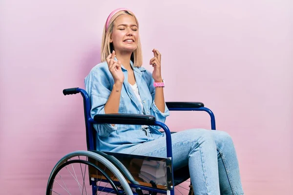 Beautiful Blonde Woman Sitting Wheelchair Gesturing Finger Crossed Smiling Hope — Stok fotoğraf