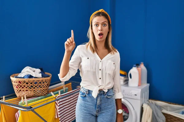 Junge Blonde Frau Der Waschküche Zeigt Mit Erhobenem Zeigefinger Auf — Stockfoto