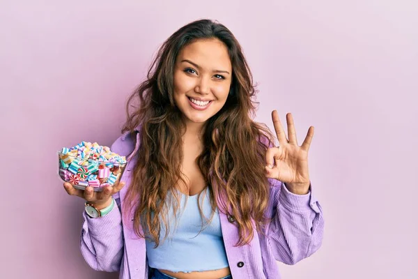 Young Hispanic Girl Holding Bowl Sugar Candy Doing Sign Fingers — 스톡 사진