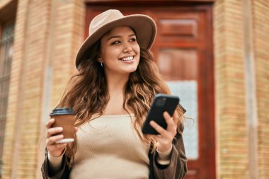 Genç İspanyol turist kadın akıllı telefon kullanıyor ve şehirde kahve içiyor..