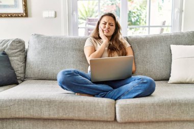 Kanepede oturan güzel, genç esmer kadın diş ağrısı ya da diş ağrısı yüzünden evde bilgisayar laptopu kullanıyor. Ağızlarına dokunuyor. dişçi 