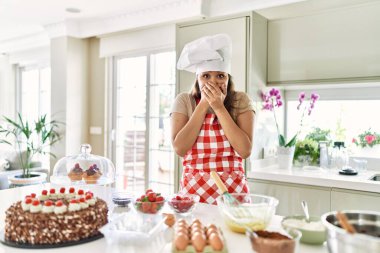 Güzel, genç, esmer pasta şefi kadın mutfakta hamur işleri pişirirken ağzını yanlışlıkla ellerle kapatırken şok oldu. gizli kavram. 