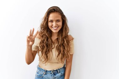 Güzel İspanyol kadın tek başına ayakta dikilirken arka plan üç numarayı gösterip işaret ederken kendinden emin ve mutlu bir şekilde gülümsüyor.. 