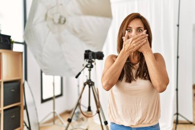 Fotoğraf stüdyosundaki genç Latin kadın yanlışlıkla ağızlarını kapatarak şok geçirdi. gizli kavram. 