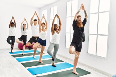 Spor merkezinde mutlu bir yoga eğitimi veren bir grup genç..
