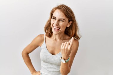 Güzel, beyaz bir kadın izole edilmiş arka planda duruyor. Buraya el hareketleriyle mutlu bir şekilde karşılamaya ve gülümsemeye davet ediyor. 