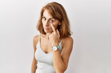 Güzel, beyaz bir kadın izole edilmiş arka planda duruyor. Gözünü dikip jestini izliyor. Şüpheli bir ifade. 