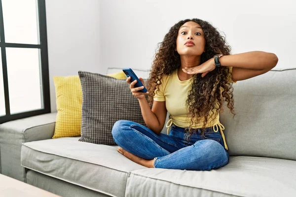 Mulher Hispânica Bonita Sentada Sofá Casa Usando Smartphone Cortando Garganta — Fotografia de Stock