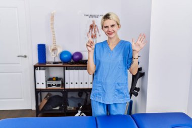 Ağrı kesici kliniğinde çalışan genç fizyoterapist kadın altı numarayı gösterip işaret ederken kendinden emin ve mutlu bir şekilde gülümsüyor.. 