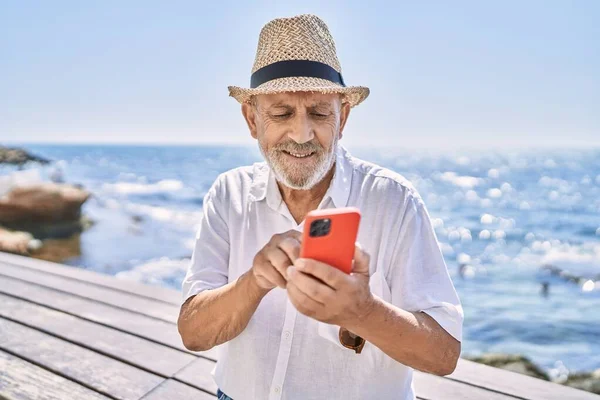 Uomo Anziano Sorridente Fiducioso Indossa Cappello Estivo Utilizzando Smartphone Mare — Foto Stock