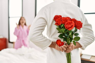 Adam yatak odasında sevgilisine bir buket gülle sürpriz yapıyor..