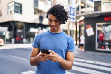 Sokakta akıllı telefon kullanan, kendine güvenen genç bir İspanyol.