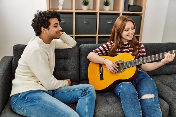 Jovem Casal Sorrindo Feliz Tocando Guitarra Clássica Sentado Sofá Casa — Fotografia de Stock