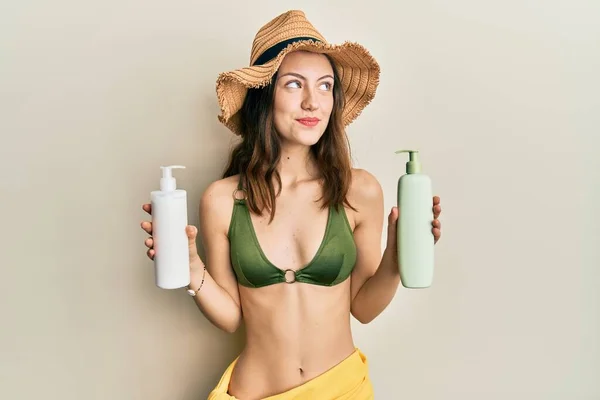 Mujer Morena Joven Con Bikini Sosteniendo Lociones Protector Solar Sonriendo —  Fotos de Stock