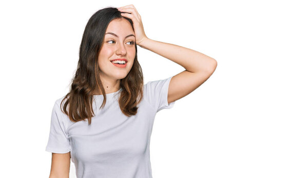 Young beautiful woman wearing casual white t shirt smiling confident touching hair with hand up gesture, posing attractive and fashionable 