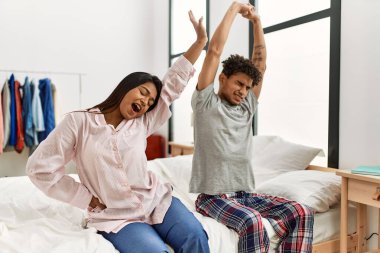 Genç Latin çift, yatak odasındaki yatakta esniyor ve kollarını esnetiyorlar..