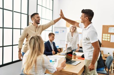 Ofiste buluşurken gülümseyen iki işçi beşlik çakıyor..