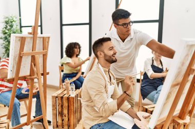 Resim öğretmeni ciddi bir ifadeyle stüdyoda boya öğrencisinin resmini çiziyor..