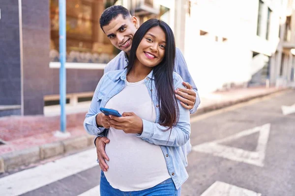 一对年轻的拉丁夫妇在街上用智能手机期待着孩子的出生 — 图库照片