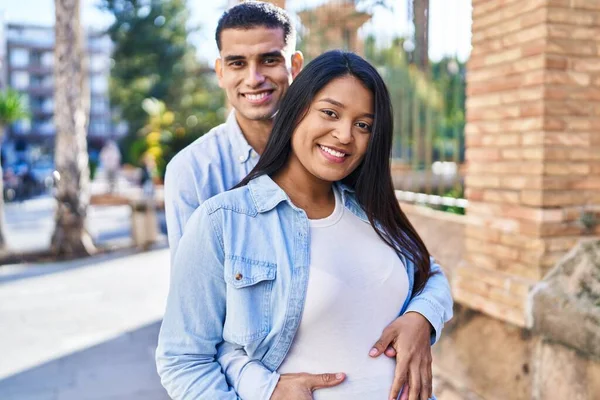 Young Latin Couple Expecting Baby Hugging Each Other Standing Street — стоковое фото