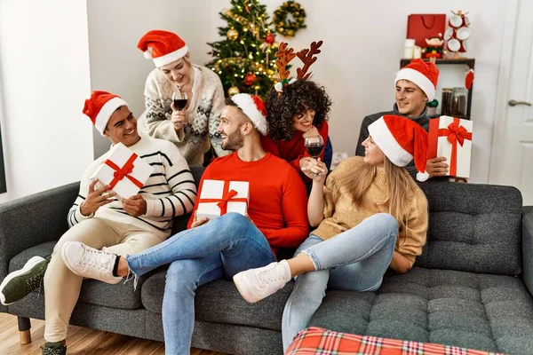 Gruppo Giovani Che Festeggiano Natale Bevendo Vino Tenendo Regali Seduti — Foto Stock