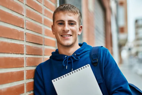 Młody Blond Student Uśmiechnięty Szczęśliwy Trzymając Notatnik Uniwersytecie — Zdjęcie stockowe