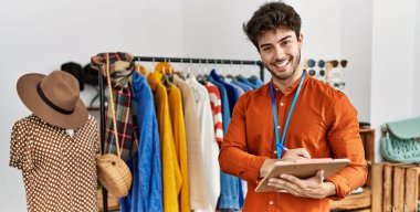 Genç İspanyol esnaf gülümsüyor. Giyim mağazasında çalışan panoya mutlu yazılar yazıyor..